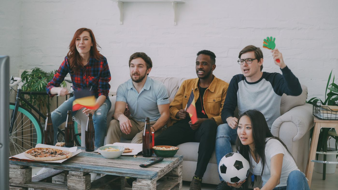 Friends watching a soccer match with snacks and drinks