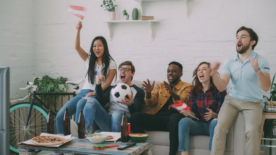 Friends on a couch cheering at a game on TV — photo by Vitaly Gariev on Pexels