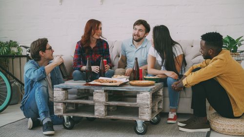 Free Group of friends sharing pizza and drinks at home, enjoying casual conversation. Stock Photo