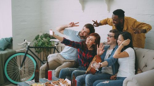Free Energetic group of friends capturing a fun moment with a selfie during a casual indoor gathering. Stock Photo