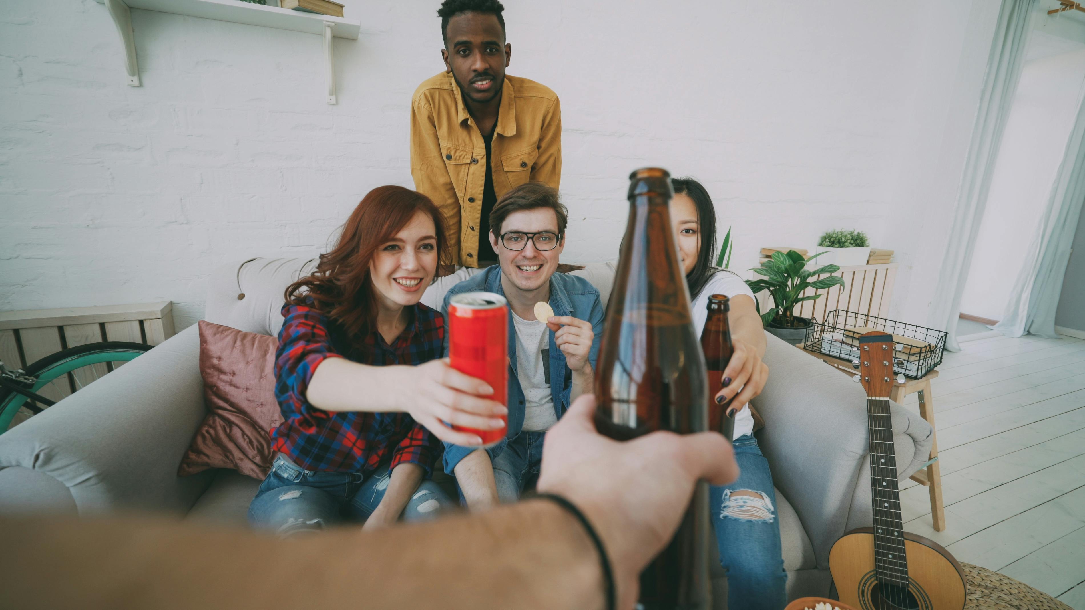 Group of friends having a casual gathering, enjoying drinks and snacks indoors.