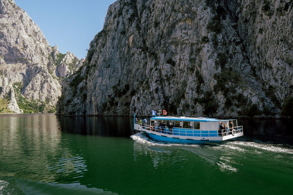 Small boat navigating the turquoise waters of Matka Canyon in North Macedonia