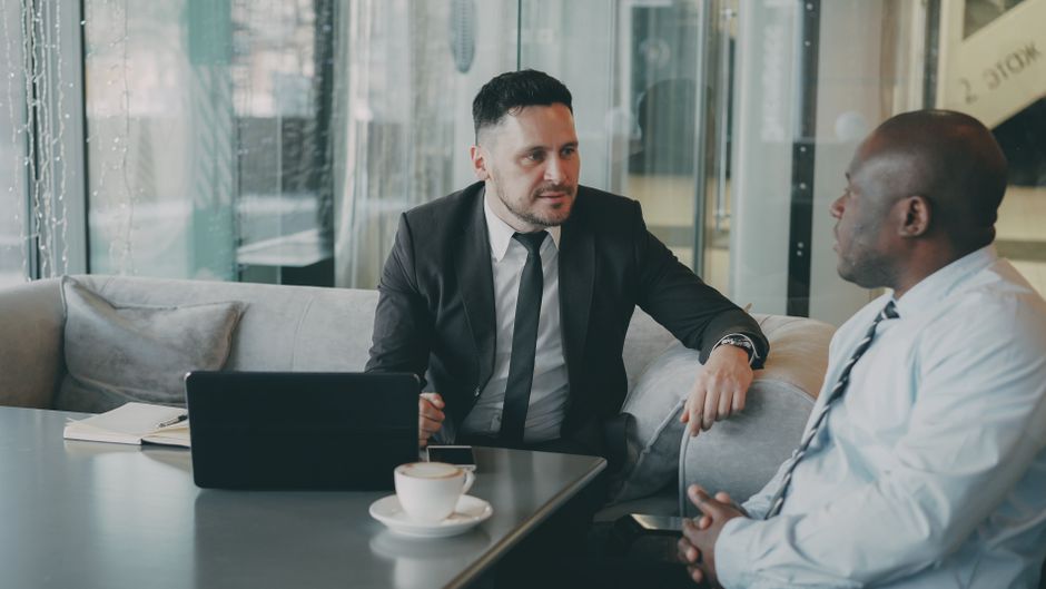 Two businessmen engaging in a discussion over coffee. Professional and focused atmosphere. Two businessmen engaging in a discussion over coffee. Professional and focused atmosphere.