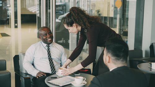 Free Business professionals enjoying coffee during a casual meeting at a café. Stock Photo