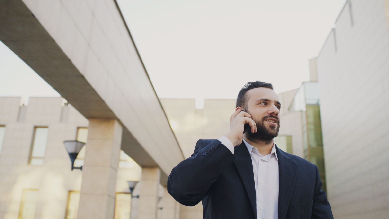 Executivo usando smartphone diante de prédio moderno, representando cobertura e mobilidade 5G