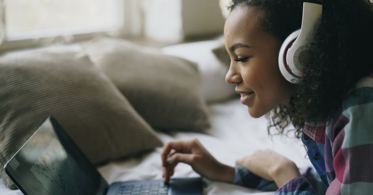 person wearing headphones listening to music on laptop at night