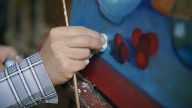 Close-up of an artist painting with vivid colors on a canvas in a studio.