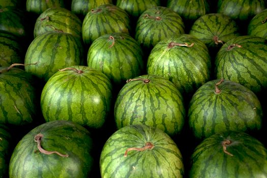 A vibrant display of green watermelons arranged closely together at an outdoor market.