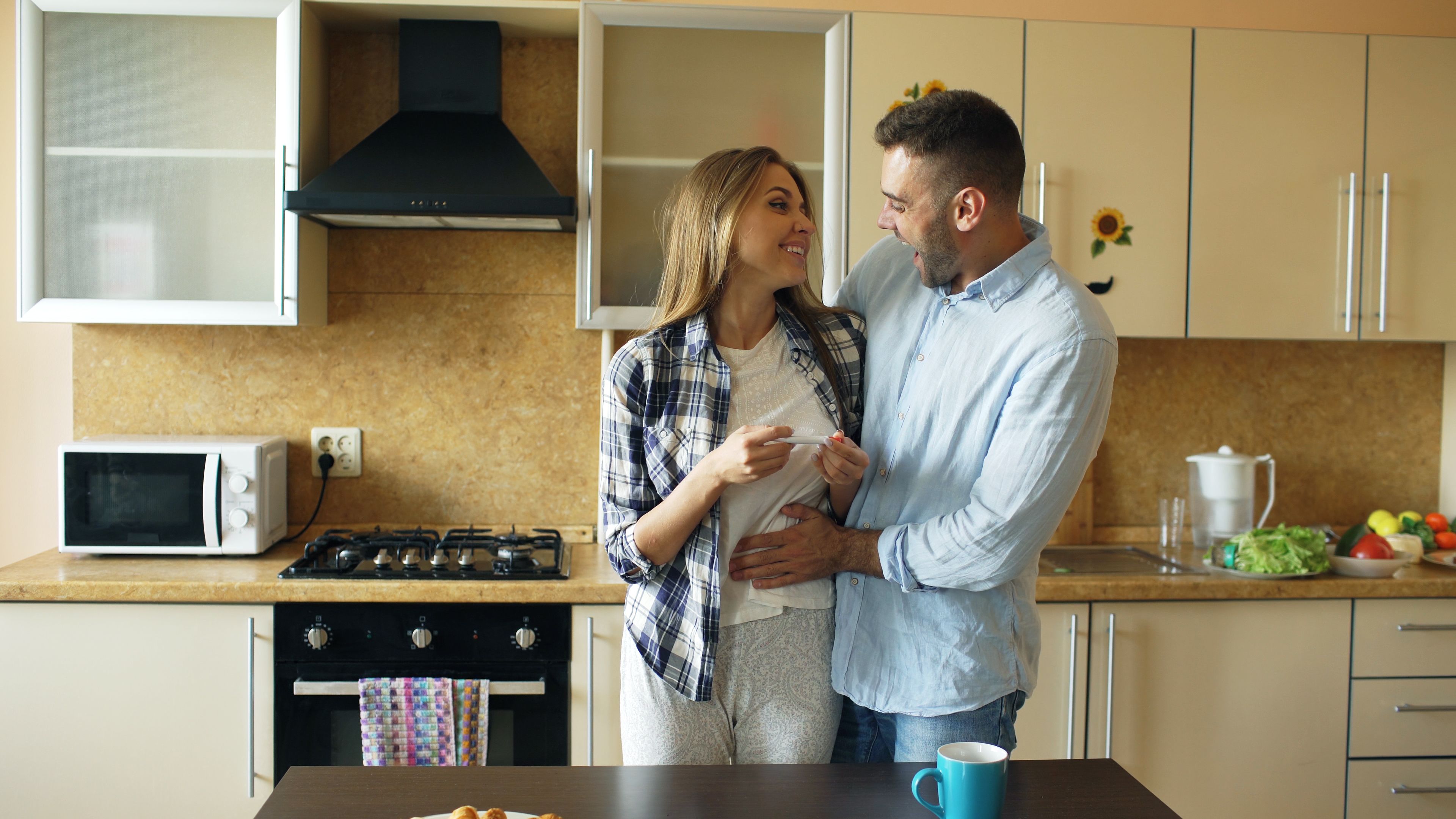 Smiling couple in cozy kitchen sharing a warm moment, morning vibes.