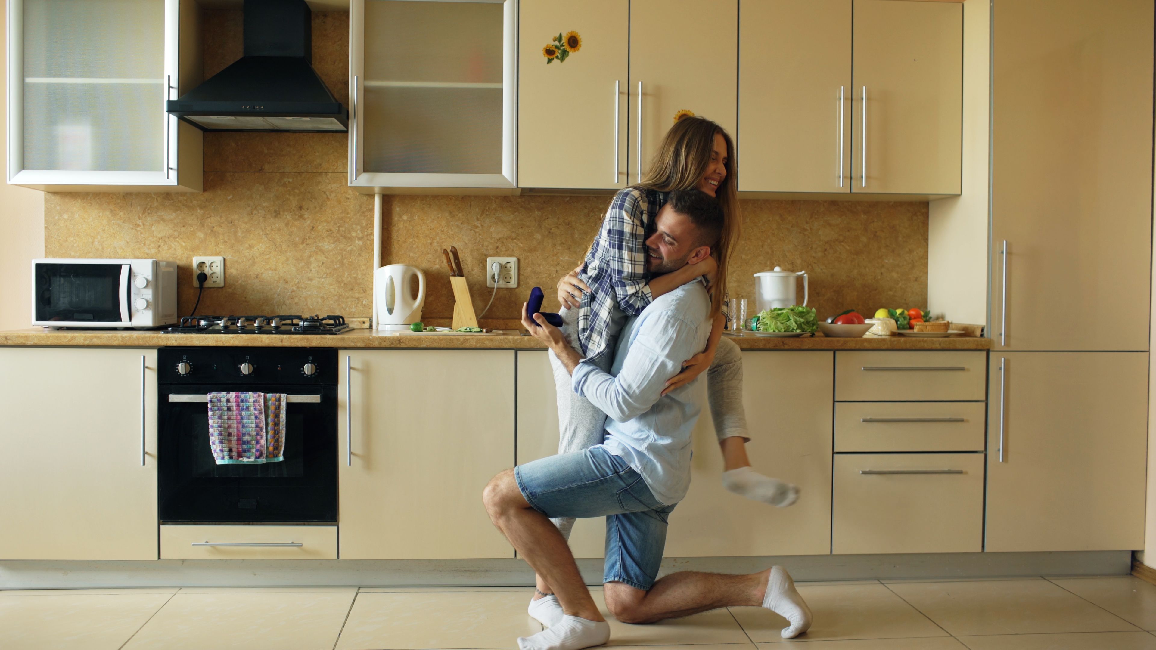 Man proposing to woman in cozy kitchen setting. Love and happiness captured spontaneously.