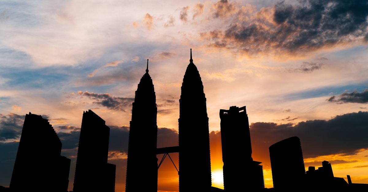 Dramatic silhouette of Kuala Lumpur landmarks against a vibrant sunset sky.