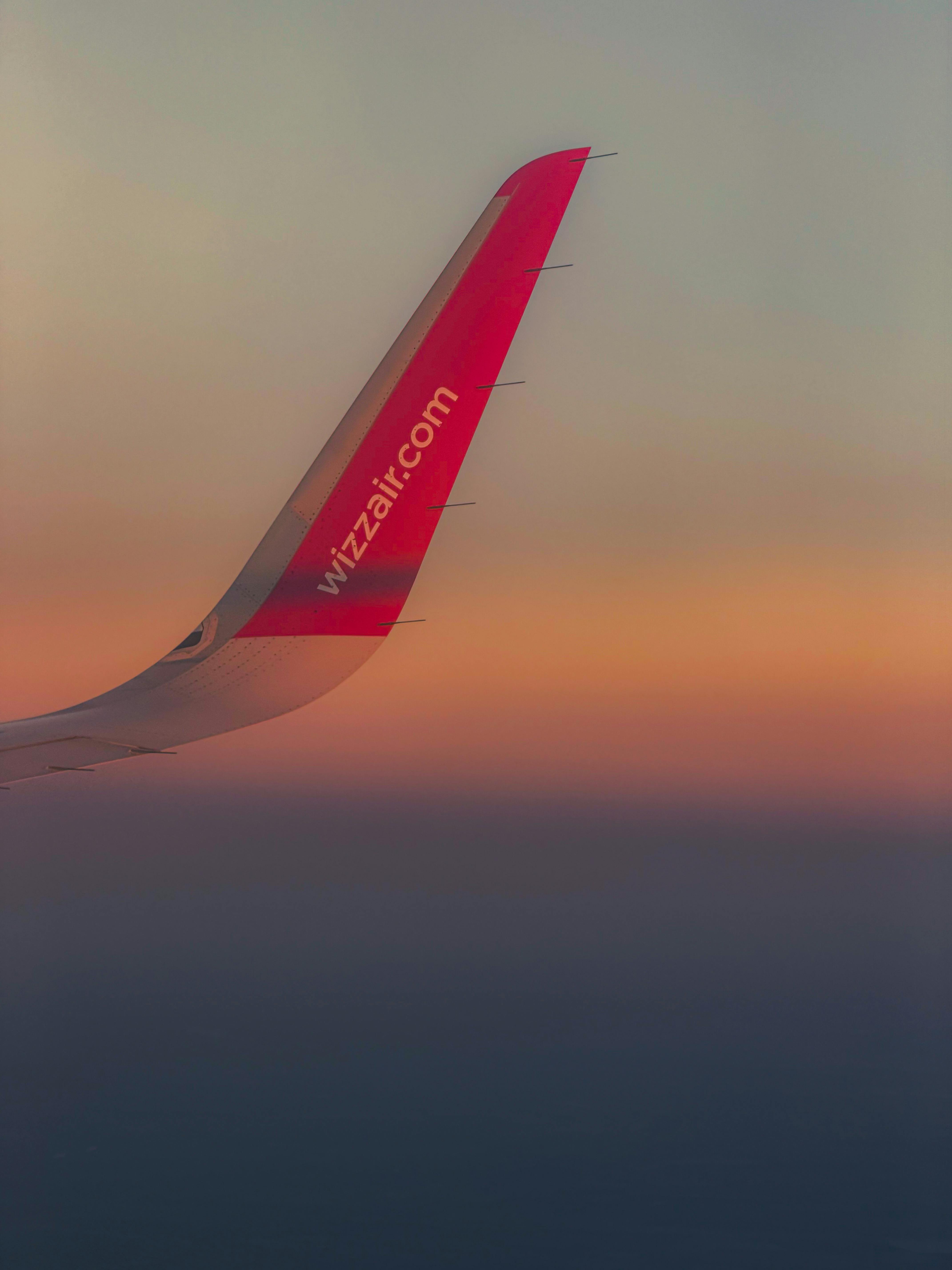A commercial airplane winglet against a vibrant sunset sky, showcasing travel and aviation.