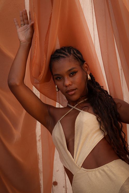 Free Sophisticated woman in stylish dress posing gracefully with flowing chiffon fabric backdrop. Stock Photo
