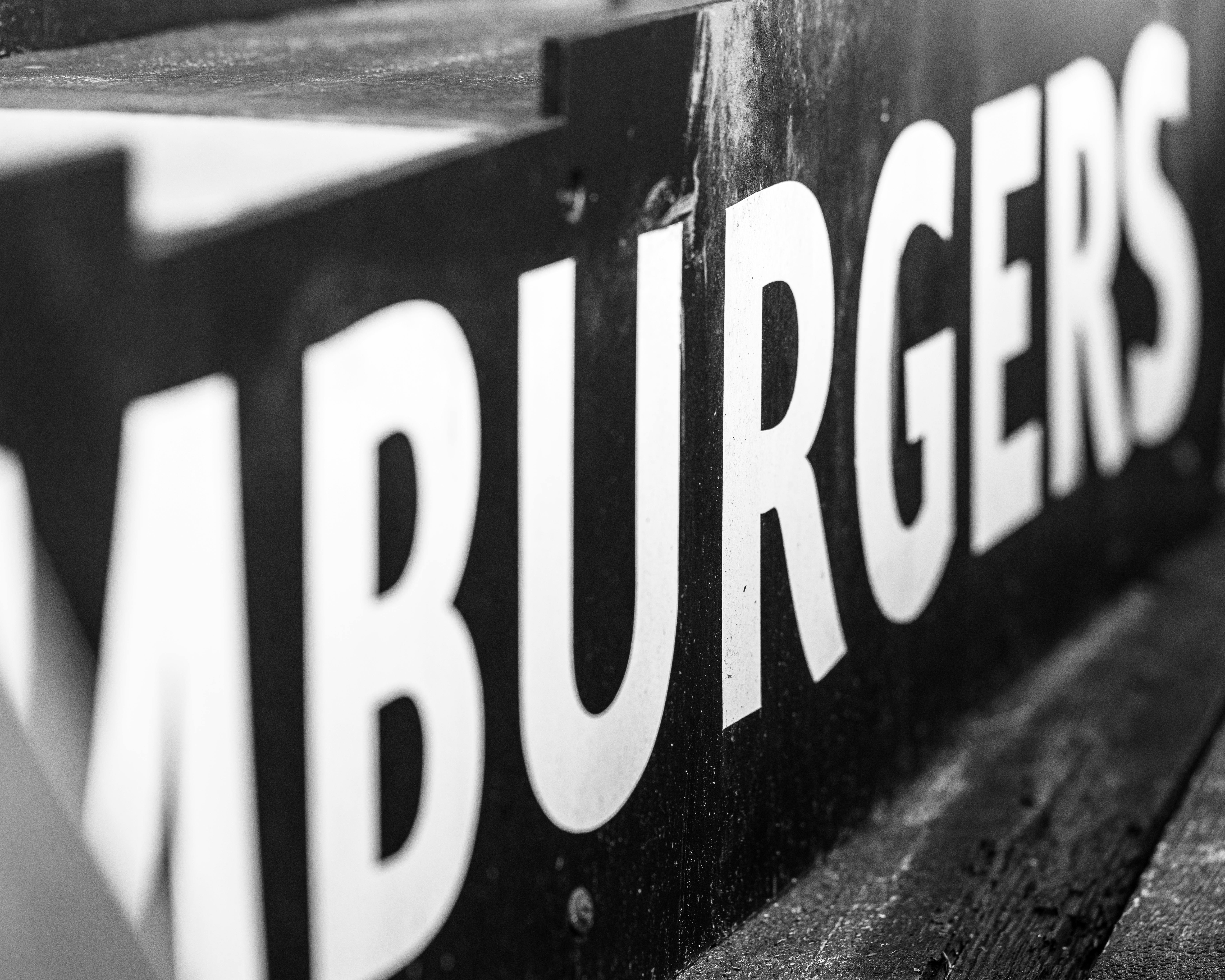 Monochrome close-up of a hamburgers sign, highlighting texture and typography.