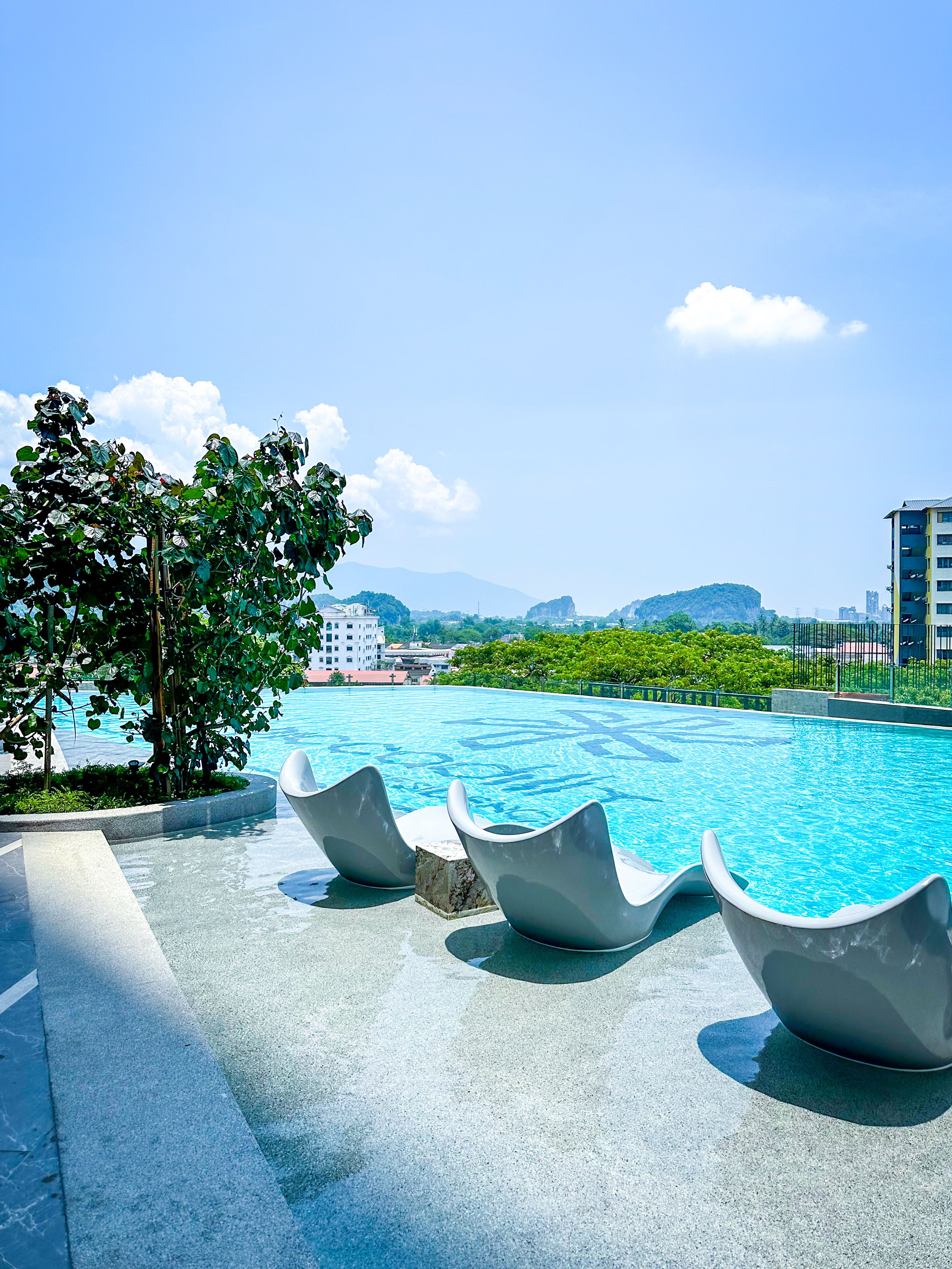 Relax by the rooftop pool with stunning city and mountain views in Ipoh, Malaysia under a clear blue sky.