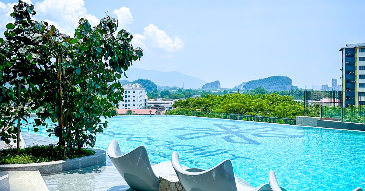 Relax by the rooftop pool with stunning city and mountain views in Ipoh, Malaysia under a clear blue sky.