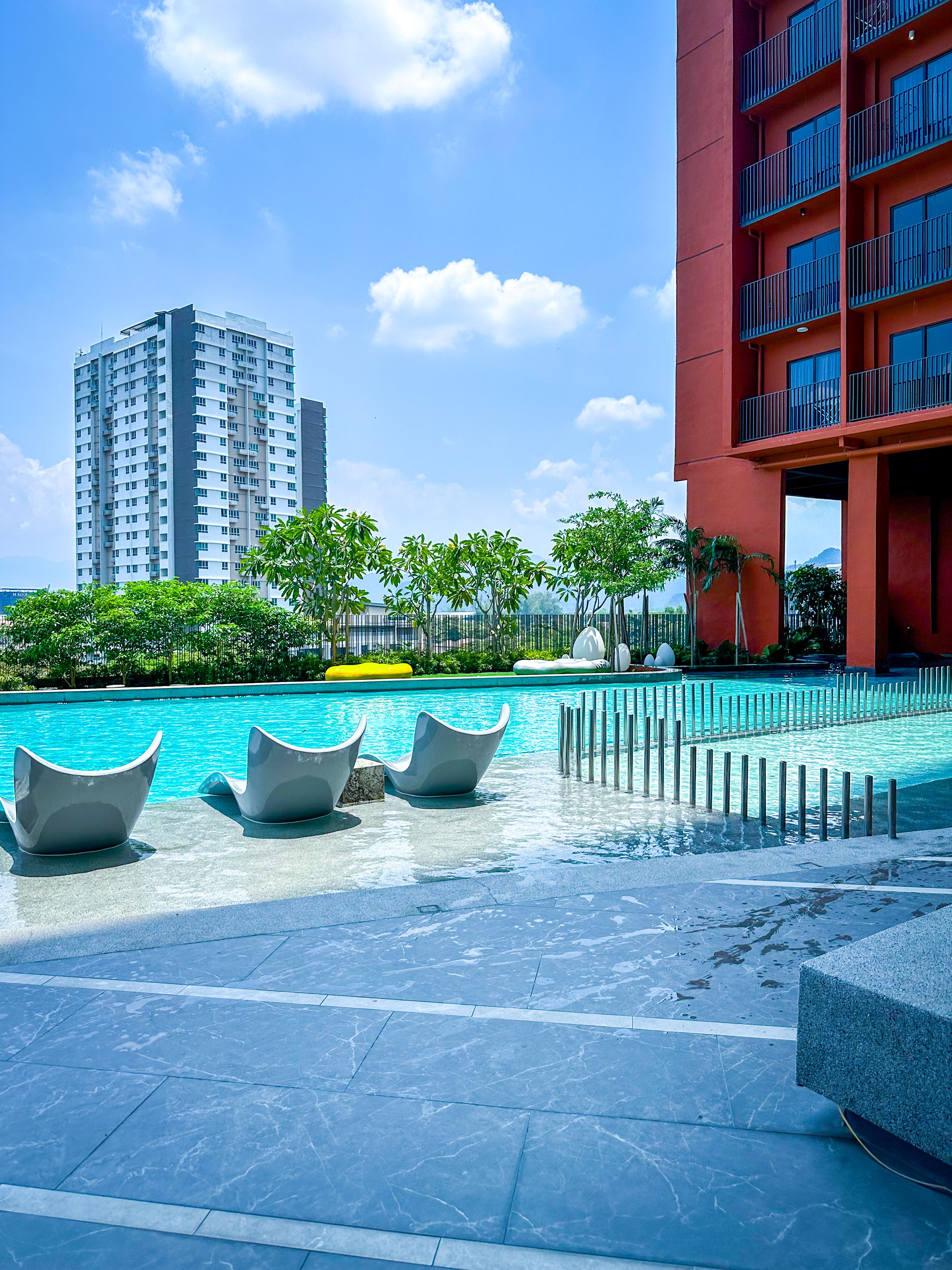 Luxurious poolside setting in a modern urban environment in Ipoh, Malaysia, under a bright blue sky.