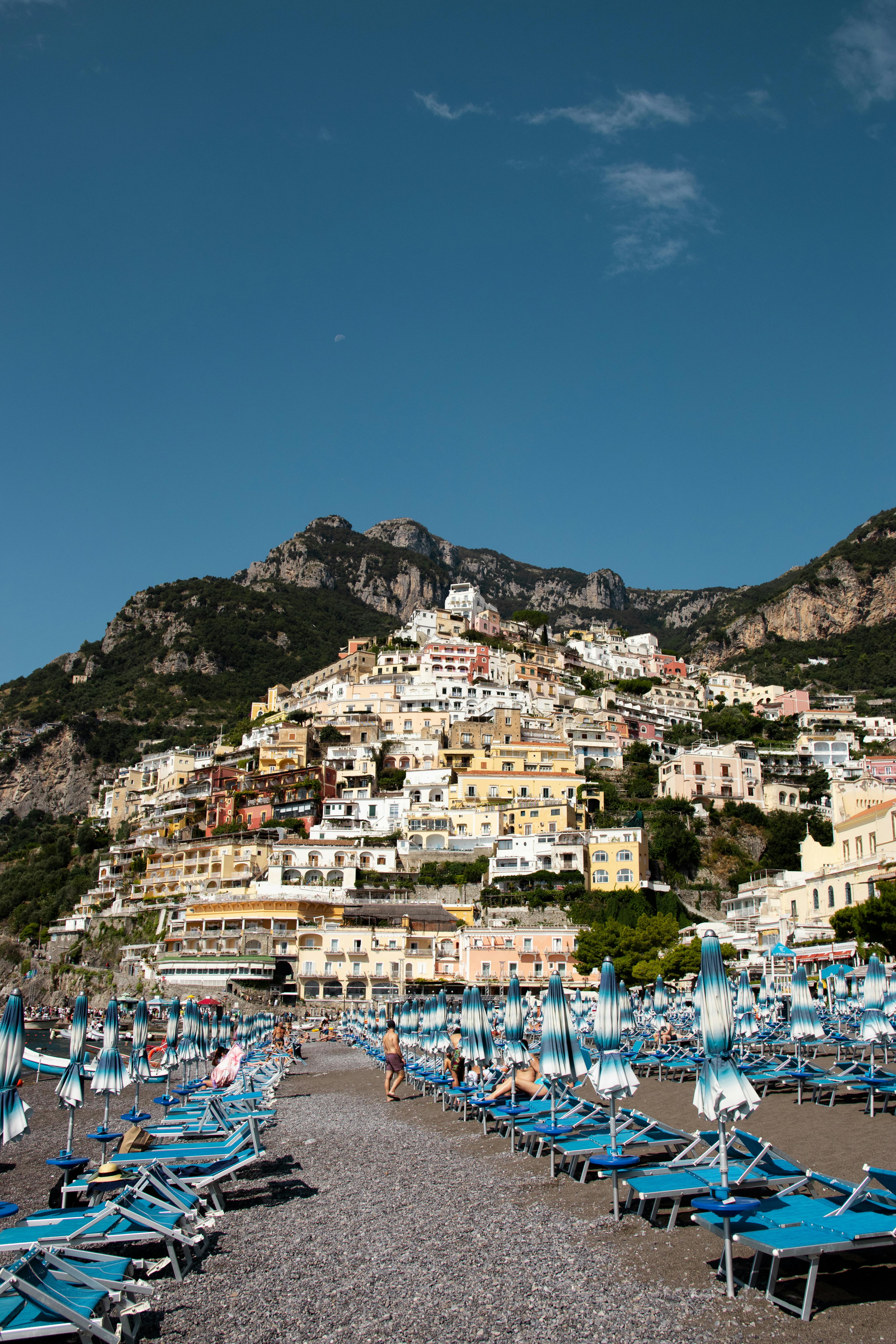 Vivid beach and town view of Positano, Italy with colorful architecture under a clear blue sky.