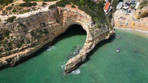 Free Stunning aerial shot of Benagil Cave with turquoise waters and sandy beach in Algarve, Portugal. Stock Photo