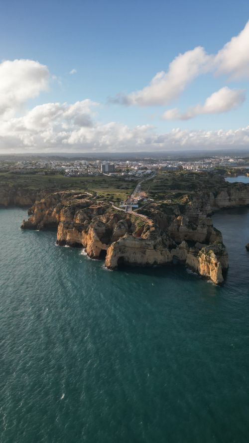 Free Scenic aerial view of the stunning cliffs and coastline in Lagos, Algarve, Portugal on a sunny day. Stock Photo