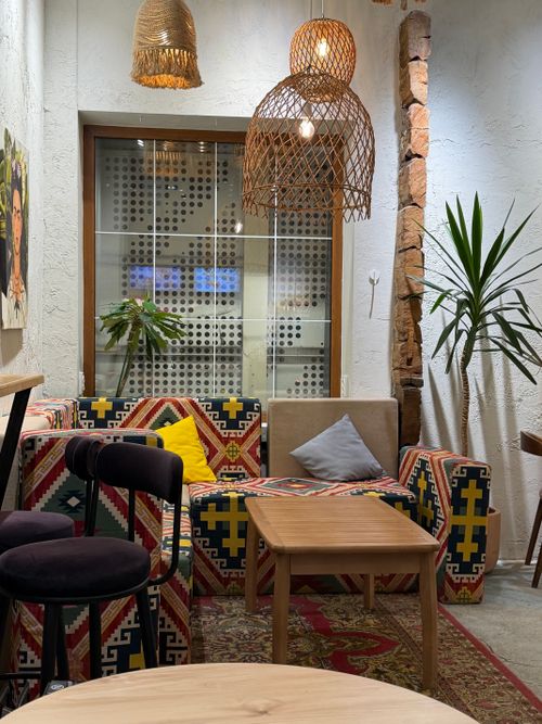 Free Chic cafe interior featuring bohemian decor, colorful textiles, and warm wooden furniture under soft lighting. Stock Photo