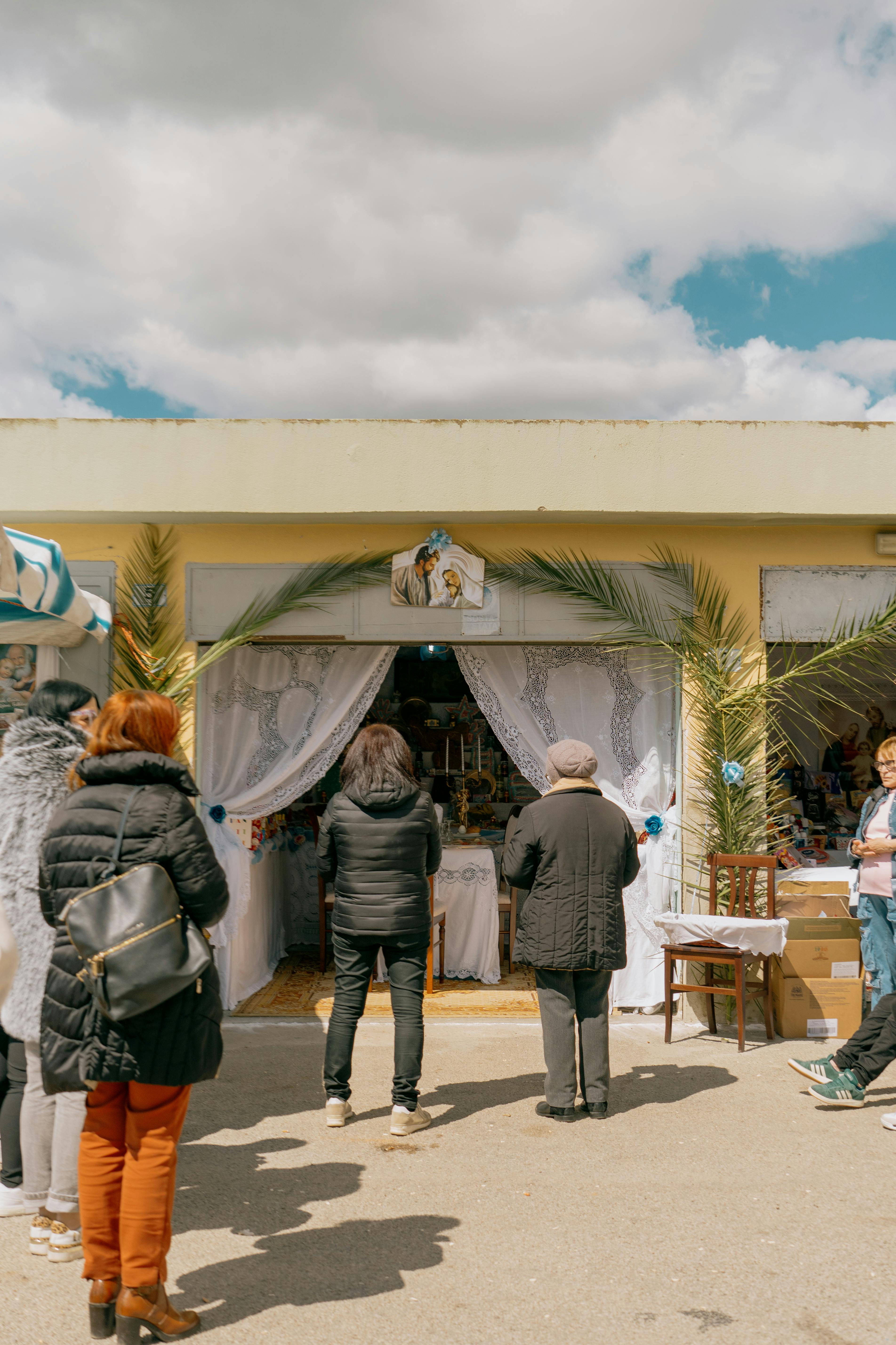 Outdoor gathering for Saint Joseph's Day festival in Gela, Sicily, with people and festive decorations.