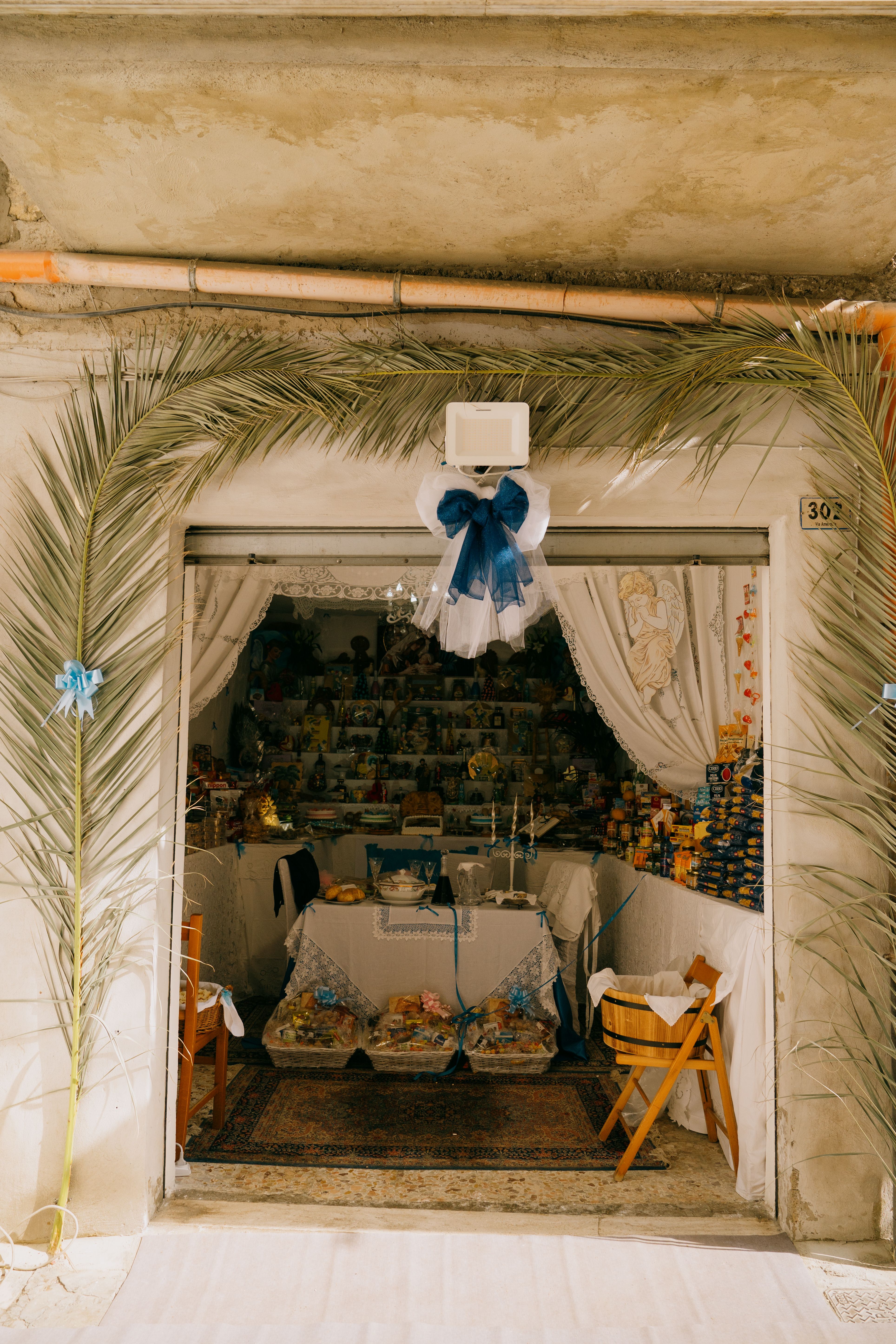 Charming Sicilian shop adorned with palm fronds in Gela, Italy.
