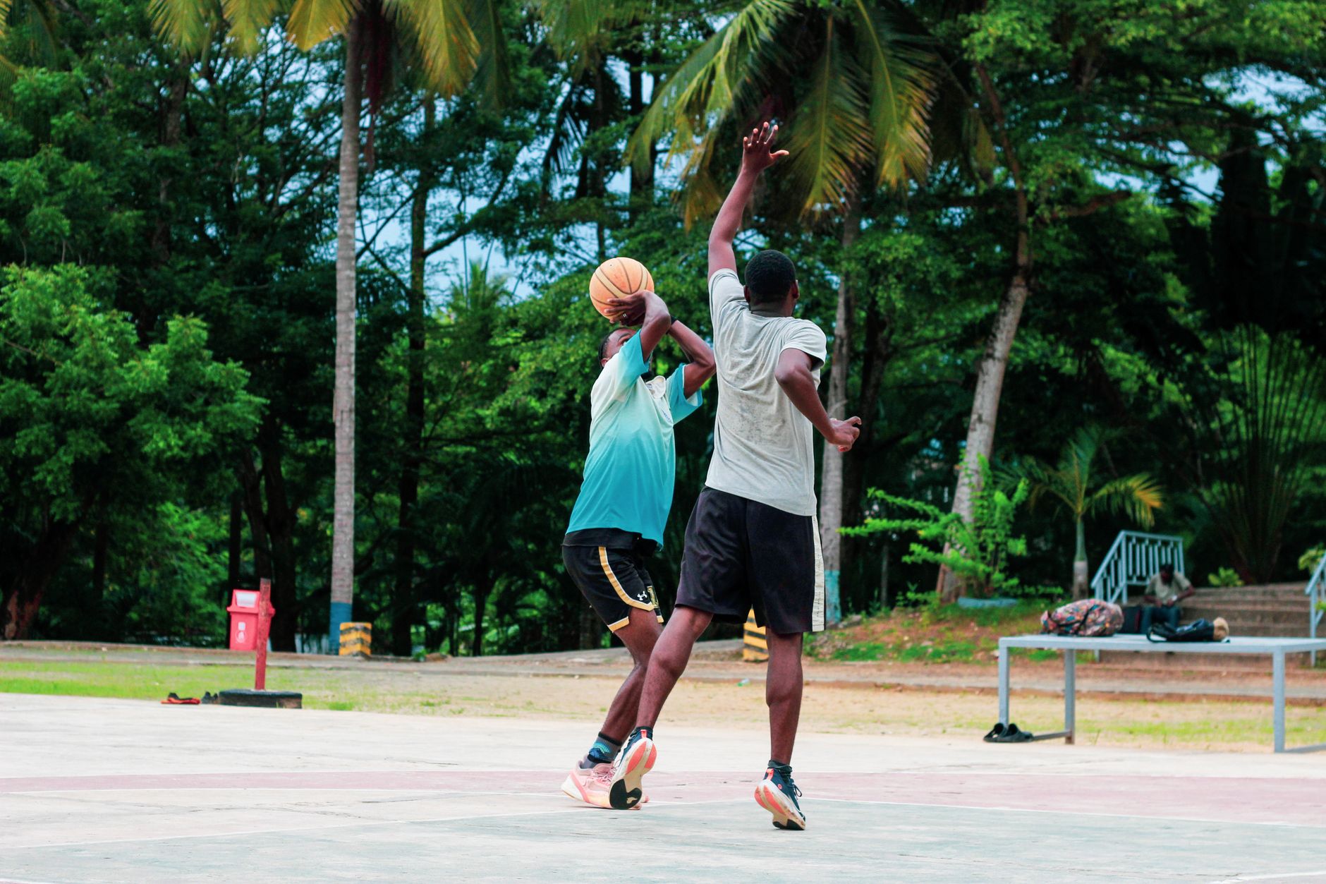 two basketball players competing in a controlled one-on-one drill beside cones inside a bright training gym