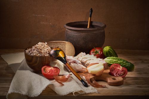 Free Cozy rustic still life featuring buckwheat, vegetables, and traditional tableware on a wooden surface. Stock Photo