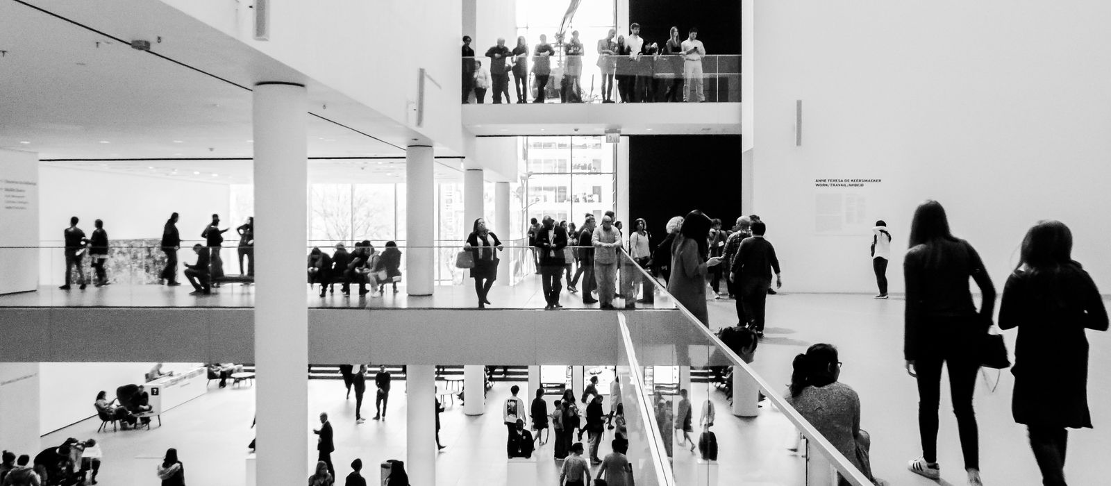 A dynamic black and white image of people in a modern museum setting.