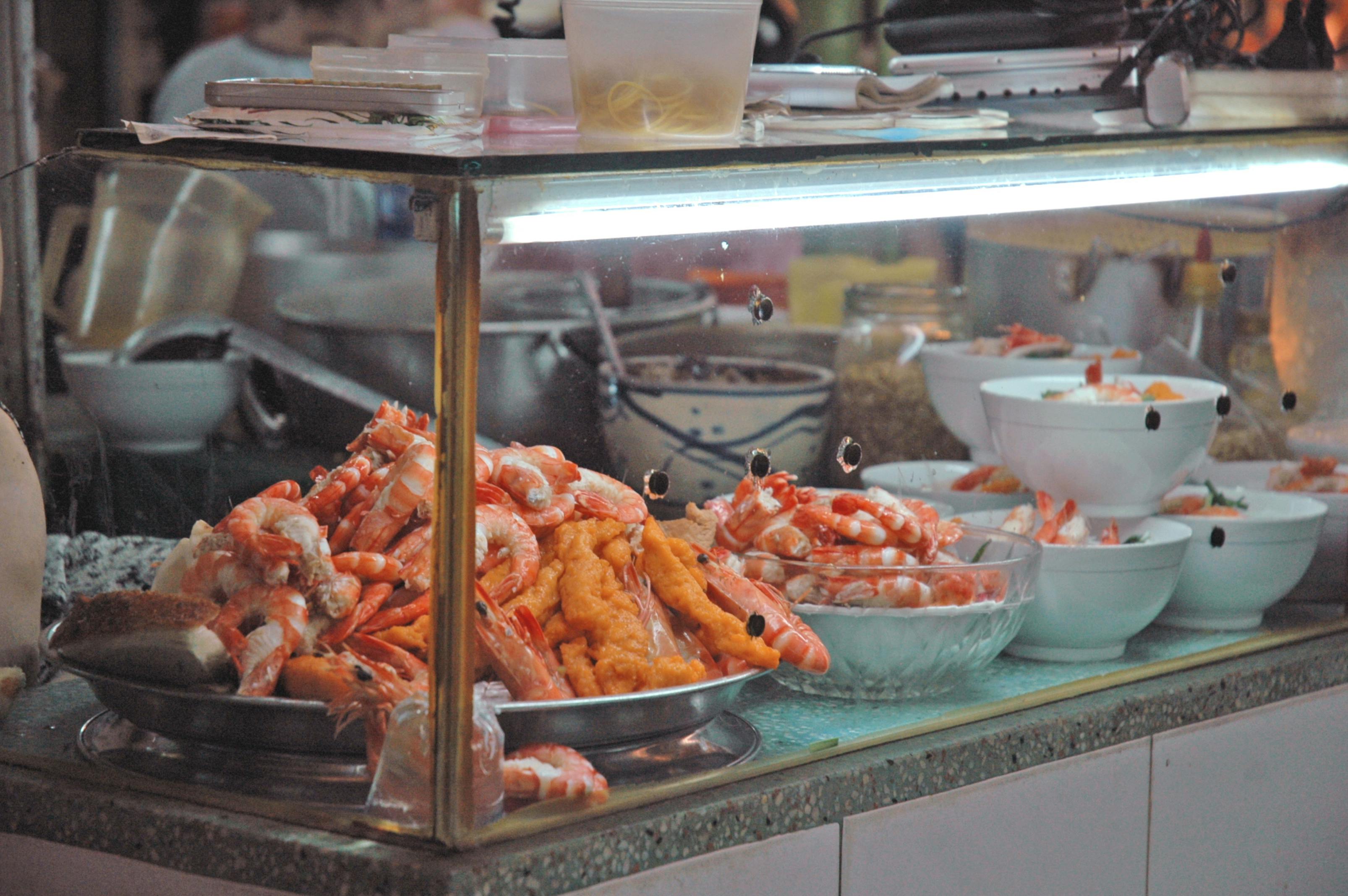 A vibrant street food stall showcasing fresh shrimp and fried seafood dishes.