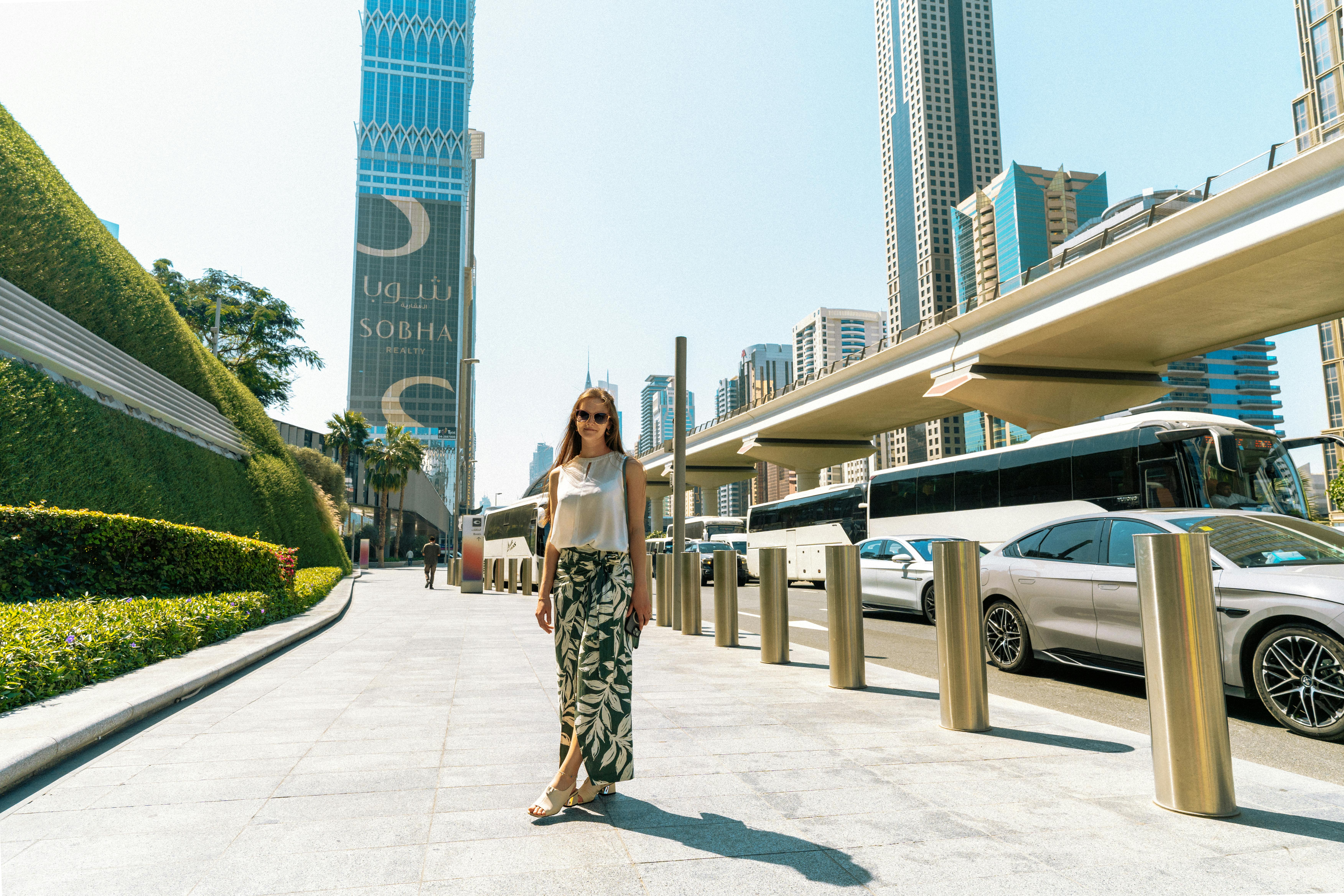 A fashionable woman strolls through a vibrant urban setting in Dubai, UAE, with skyscrapers and mode
