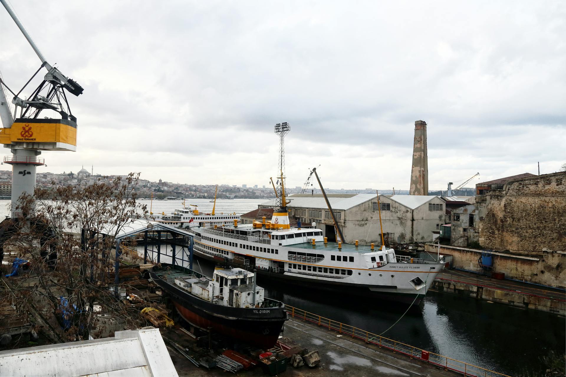 A vibrant industrial shipyard scene featuring moored ferries, towering cranes, and urban background.