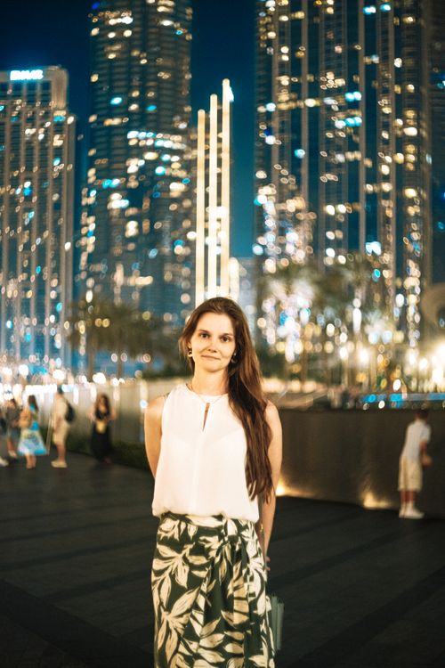 Free Stylish woman poses at night with Dubai's illuminated skyline in the backdrop, showcasing urban elegance. Stock Photo