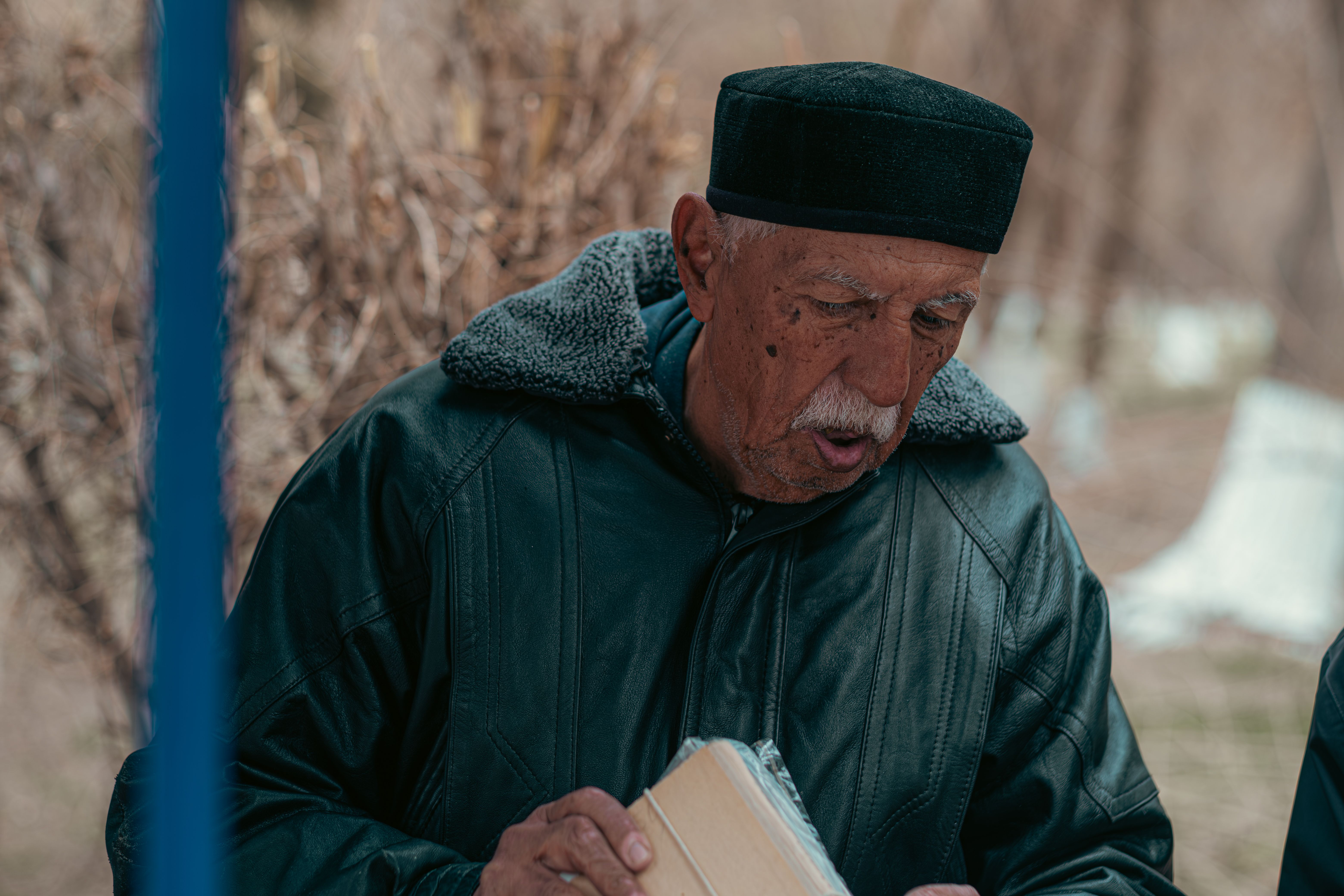 Portrait of an elderly man wearing traditional Uzbek attire in an outdoor setting.