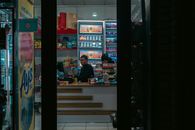 Interior of a convenience store in Uzbekistan with two adults manning the counter at night.