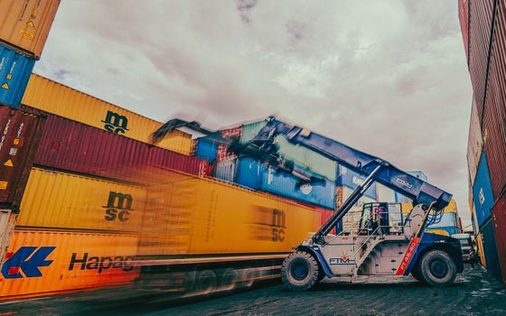 Dynamic scene of containers being loaded by a crane in an industrial shipping yard.