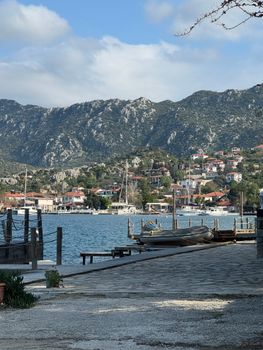 Picturesque harbor scene with boats and mountains at Kas, Turkey under a bright sky.