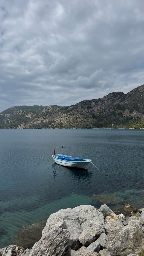Free A tranquil scene of a lone boat on the Aegean Sea near Marmaris, Turkey, with scenic mountains. Stock Photo