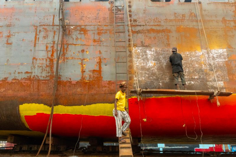 Operai che verniciano la carena di una barca in cantiere
