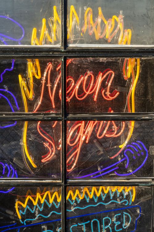 Neon Sign Window Frame Vibrant Neon Signs on Urban Window · Free Stock Photo