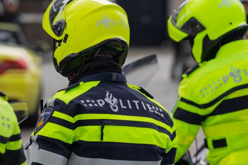 Free Dutch police officers in reflective uniforms seen from behind, perfect for law enforcement themes. Stock Photo
