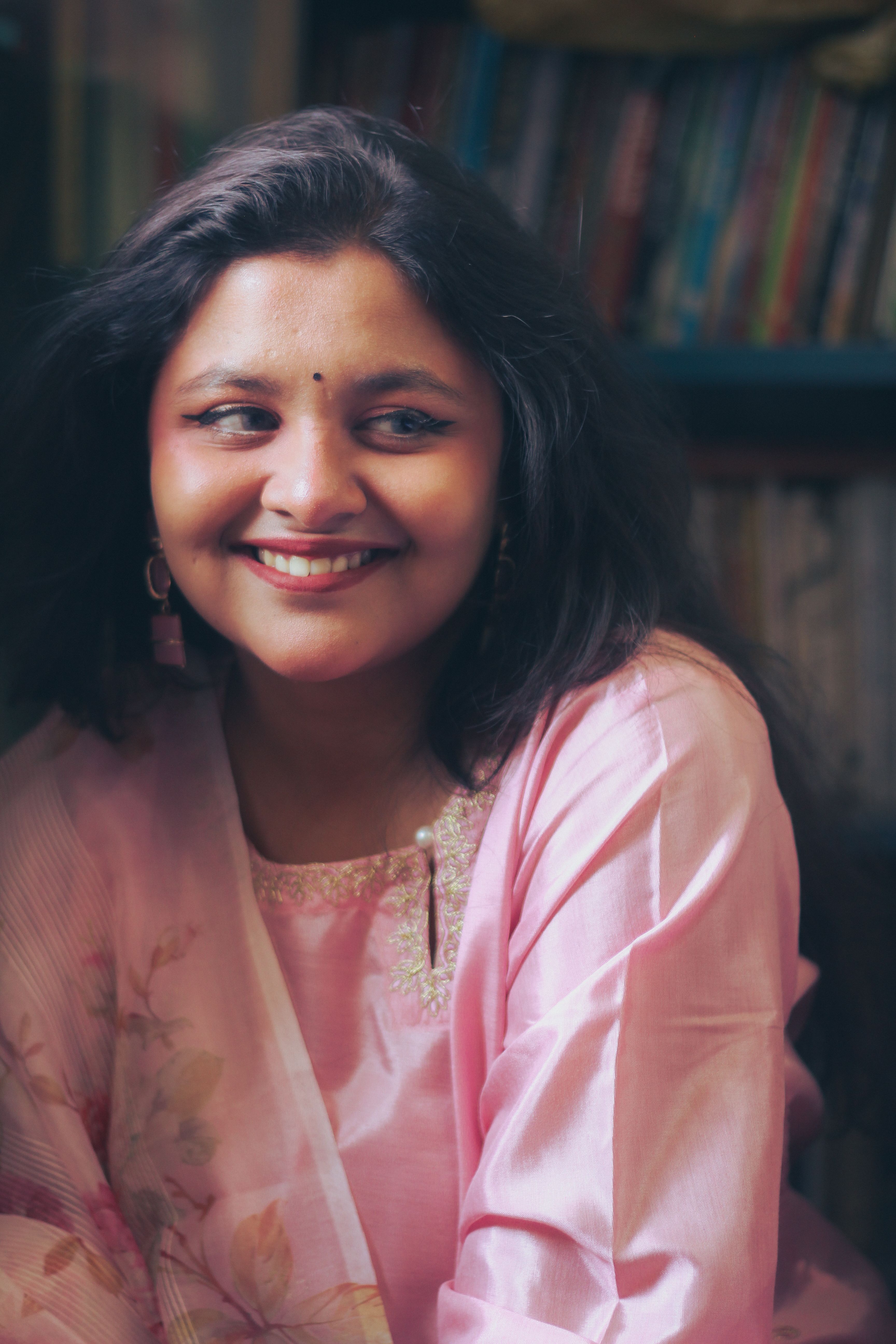 Beautiful woman in a pink dress smiling warmly, captured indoors in Dhaka, Bangladesh.