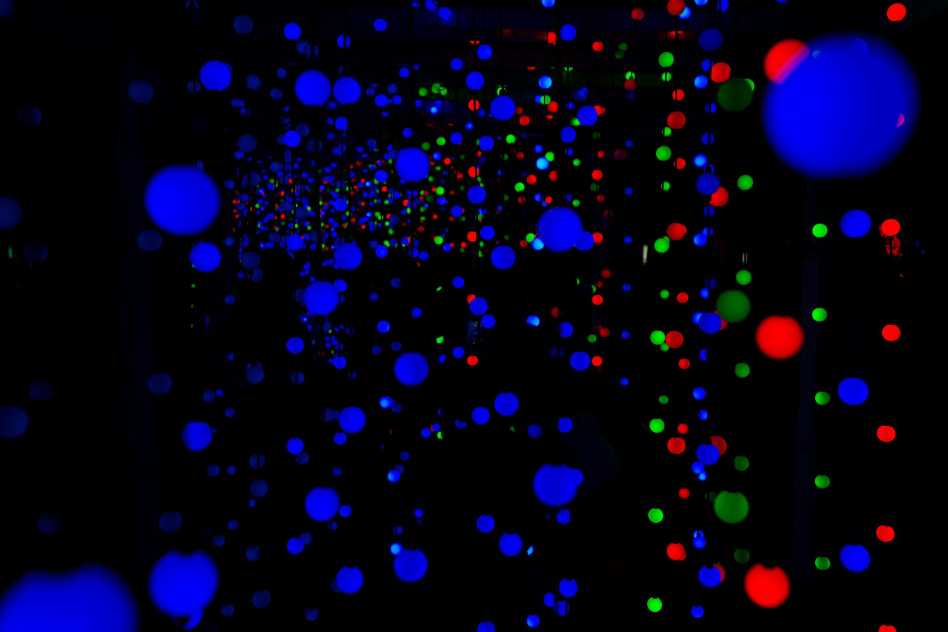 Abstract display of vivid blue, red, and green light spheres in dark space.