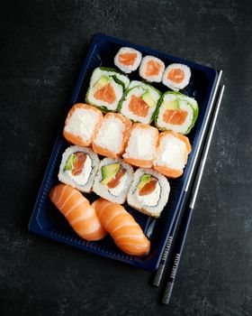 A beautifully arranged sushi platter featuring salmon and avocado rolls with chopsticks.