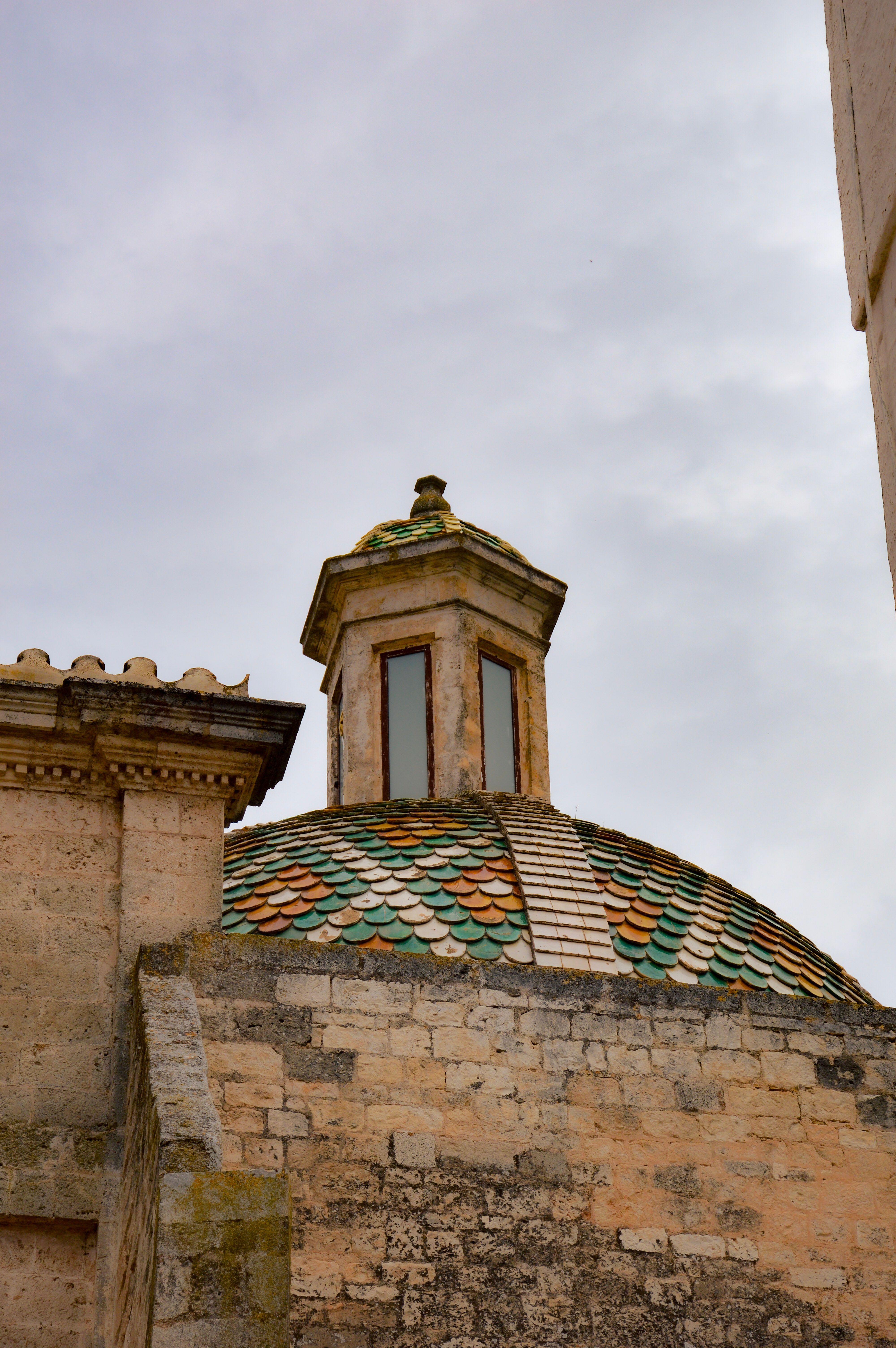Captivating shot of the colorful tiled dome in Ostuni, Italy, showcasing its unique architectural details.