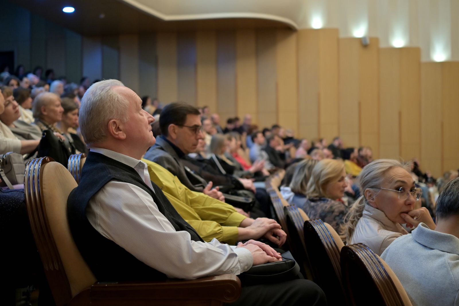 A diverse audience listening attentively during an indoor conference session