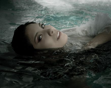 Artistic portrait of a woman floating gracefully in water, evoking elegance and serenity.