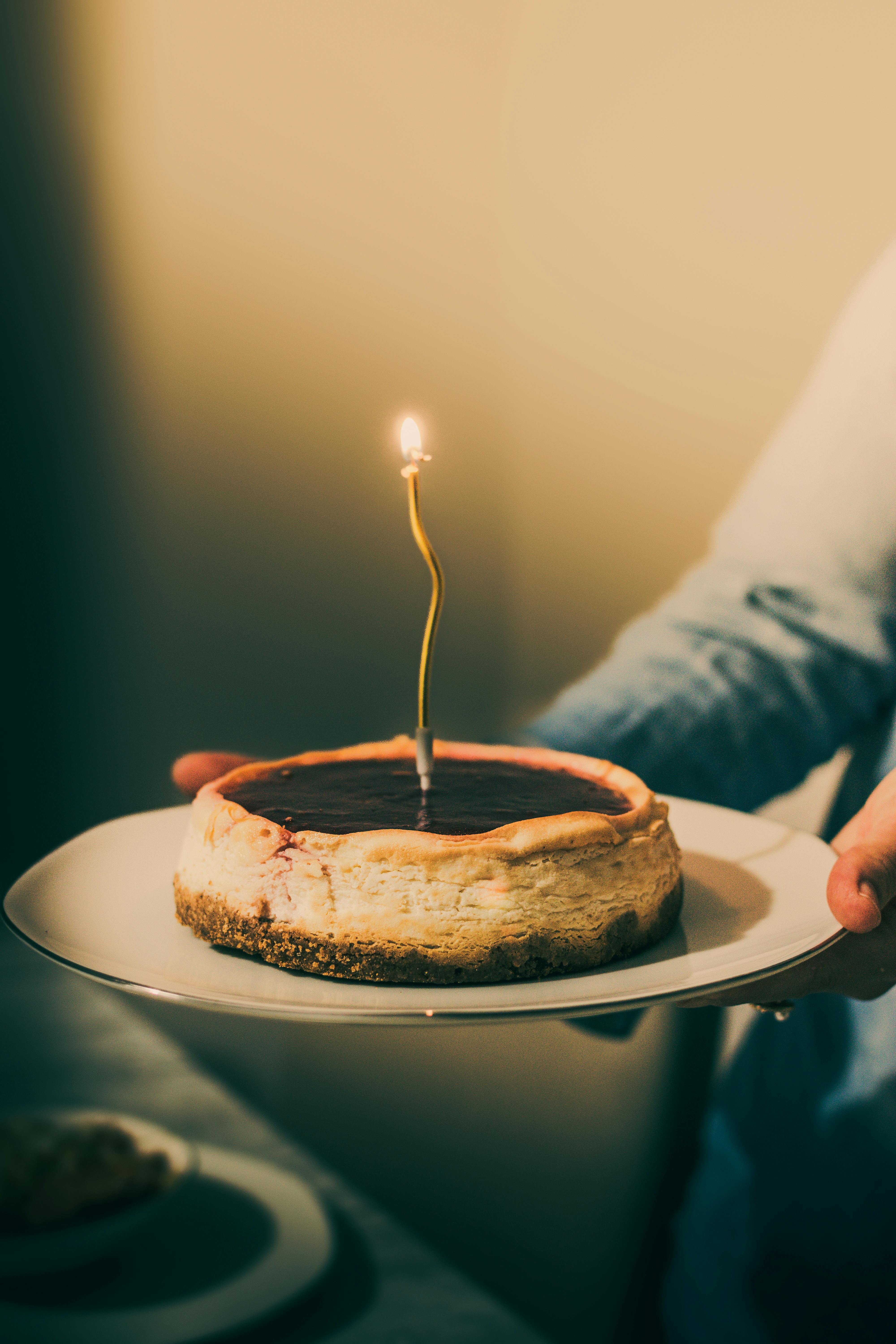 A delicious cheesecake with a lit candle, perfect for a cozy birthday celebration.