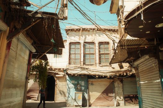 A sunlit alley in Damascus' Old City with vintage architecture and closed shops.